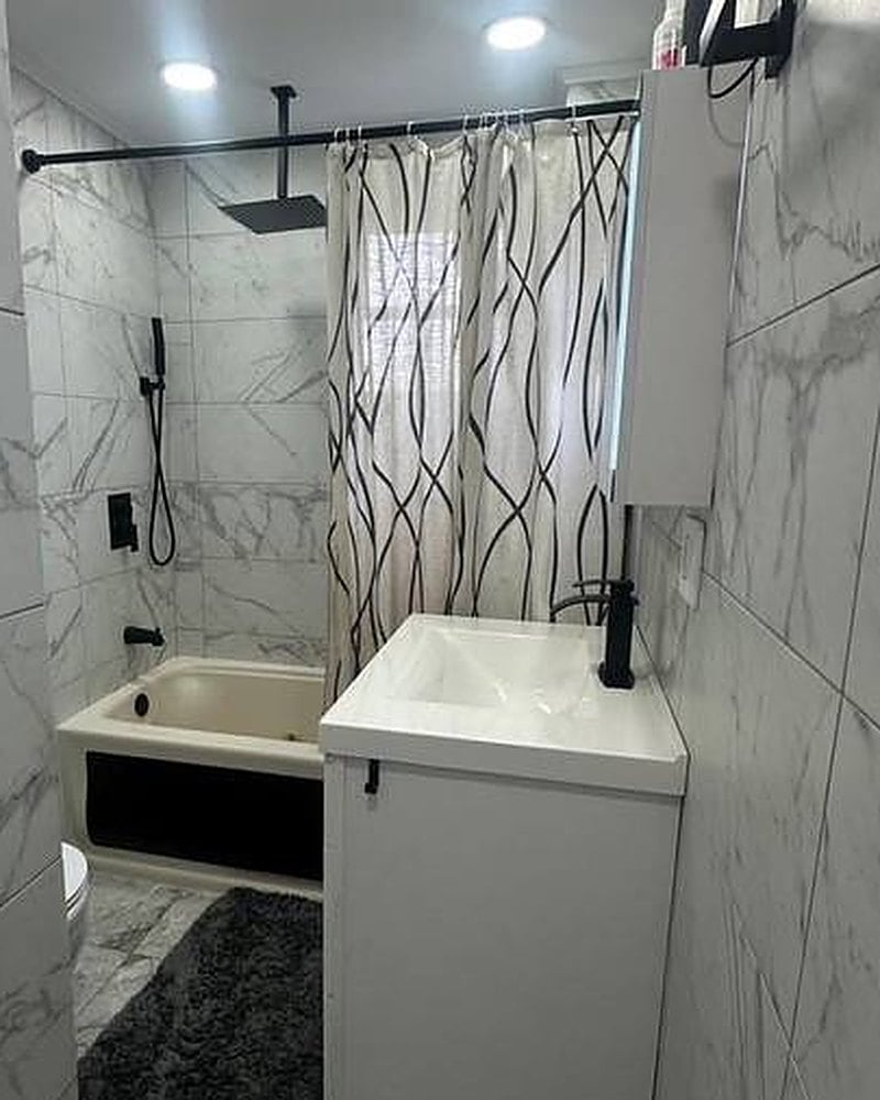Remodeled bathroom with marble-look tile and matte black fixtures