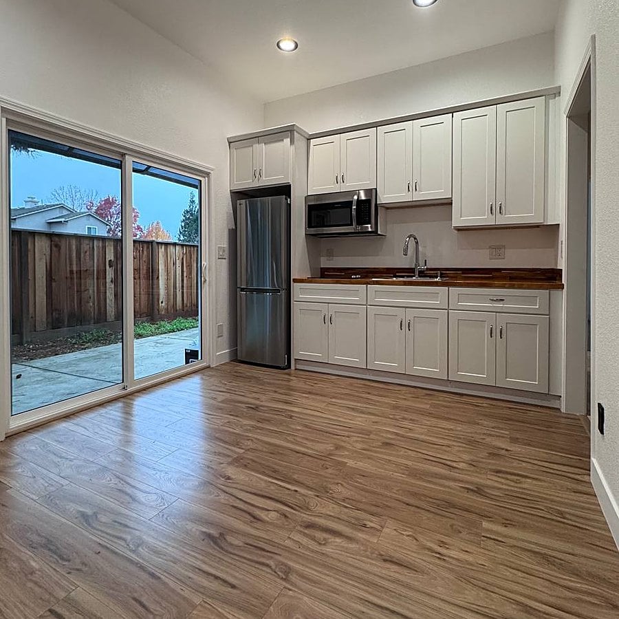 After: guest kitchen with white shaker cabinets, stainless appliances and sliding doors to the backyard